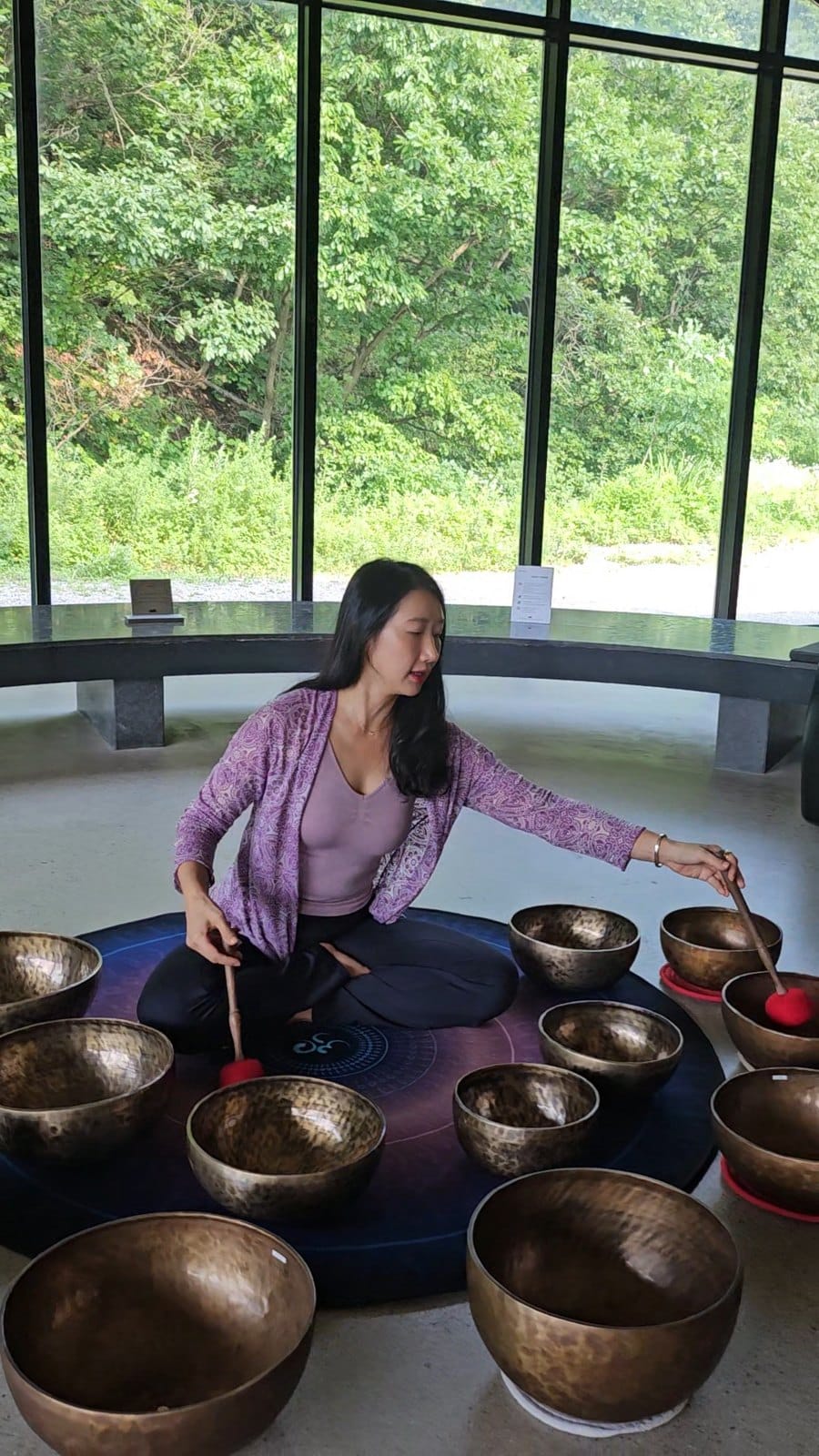숲 앞에서 싱잉볼을 연주하는 모습
